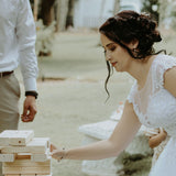 Bride playing on-site Jenga game for weddings with large wooden blocks outdoors