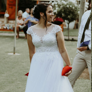 Bride holding red bean bag playing with cornhole set for on-site weddings in outdoor garden