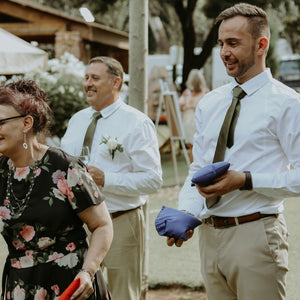 Guests playing cornhole set for on-site weddings with blue and red bean bags at outdoor wedding event