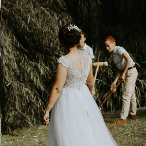 Bride in detailed white wedding dress playing croquet with children outdoors croquet rental forevermore moments