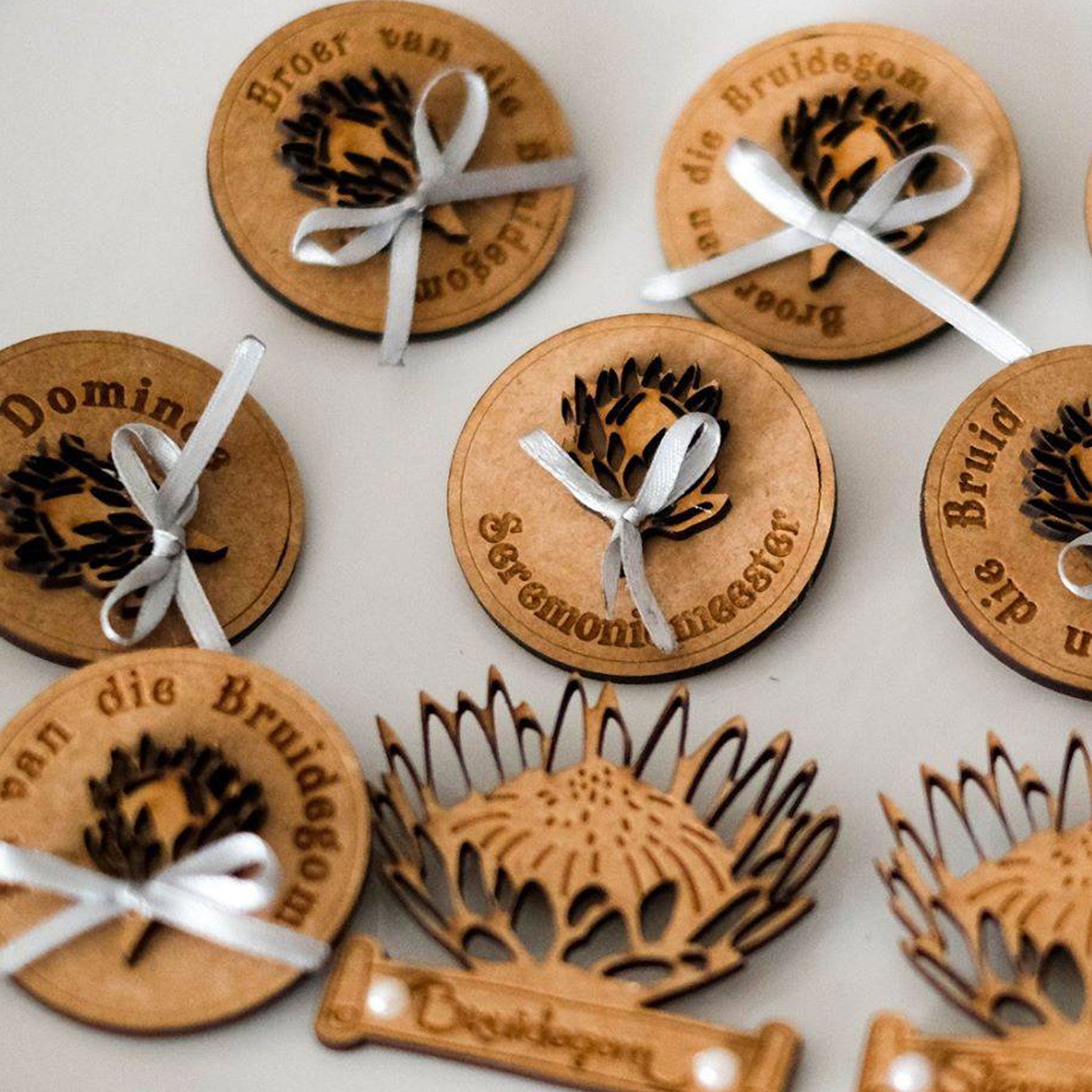 Forevermore Momentos custom laser-cut wedding pins with floral designs and white ribbon bows