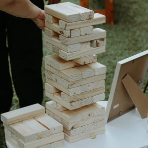 On-site Jenga game for weddings with large wooden blocks stacked on a table outdoors