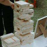On-site Jenga game for weddings with large wooden blocks stacked on a table outdoors