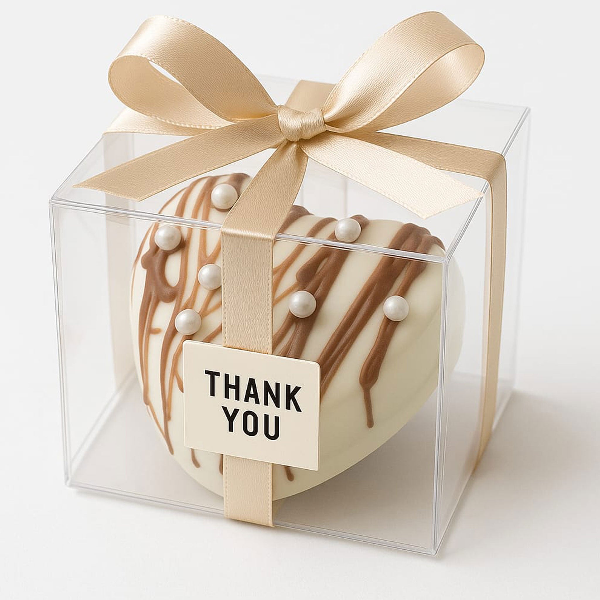 Handmade chocolate bomb gift heart-shaped with white pearls and caramel drizzle in clear gift box