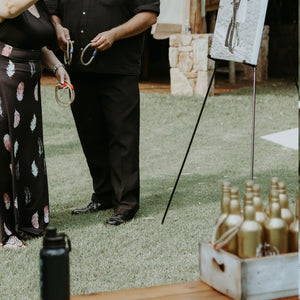 Couple playing on-site wedding game ring toss rental with rope rings on grass lawn outdoors