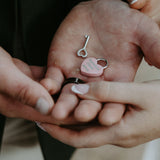 Hands holding a pink heart-shaped padlock and key symbolizing personalized love locks wedding gift