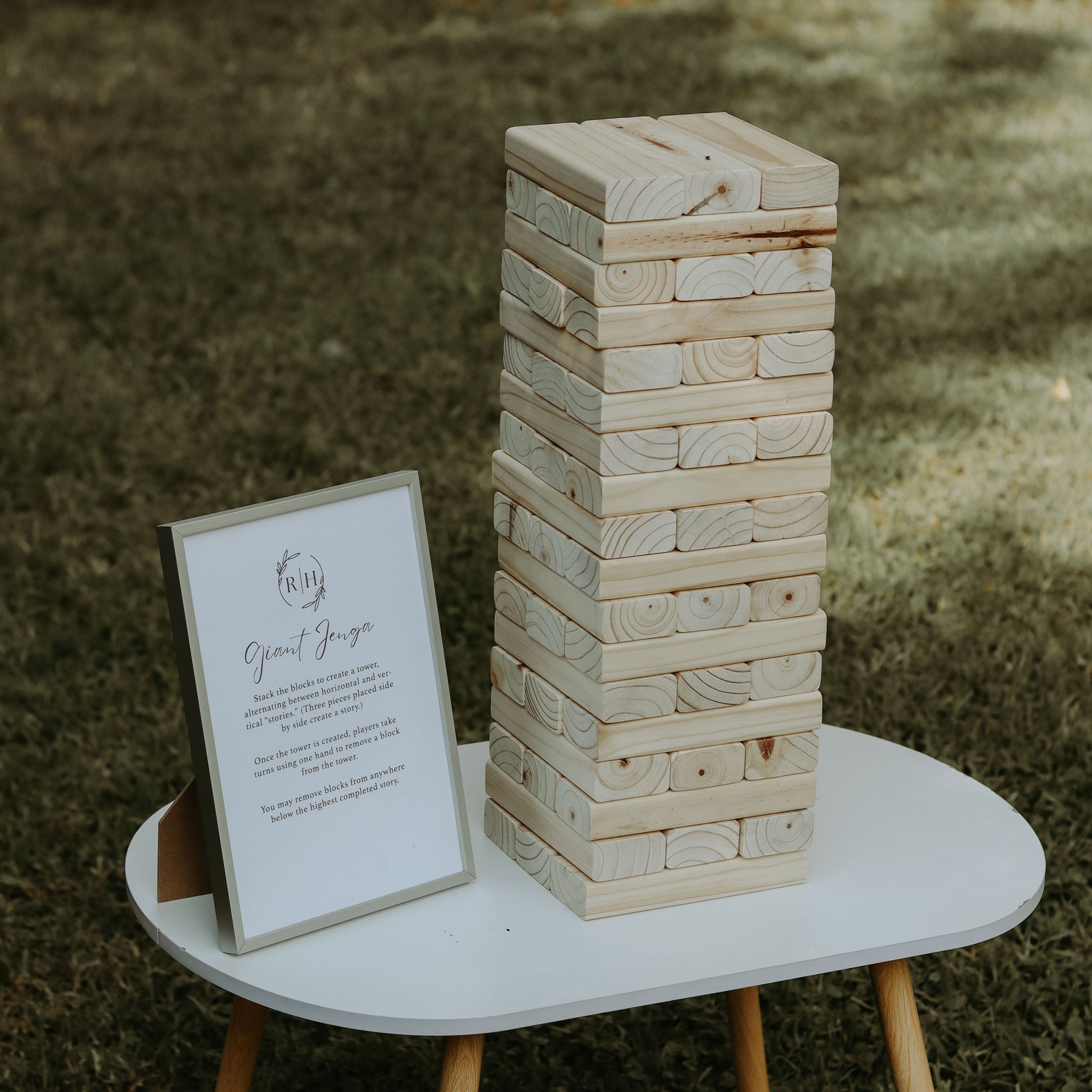 Stacked wooden blocks for on-site Jenga game for weddings displayed on a white table outdoors