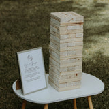 Stacked wooden blocks for on-site Jenga game for weddings displayed on a white table outdoors