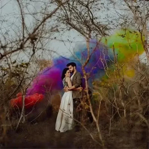 Colorful wedding party smoke bomb props creating a vibrant backdrop for a couple in an outdoor setting