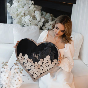 Wooden heart wedding guest book displayed by a bride with personalized initials and decorative hearts