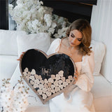 Wooden heart wedding guest book displayed by a bride with personalized initials and decorative hearts