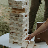 On-site Jenga game for weddings with large wooden blocks stacked on a white table